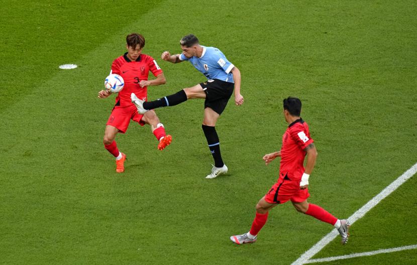  Pemain Uruguay Facundo Pellistri (tengah) menendang bola saat pemain Korea Selatan Kim Jin-su, pergi, menantangnya selama pertandingan sepak bola grup H Piala Dunia antara Uruguay dan Korea Selatan, di Stadion Education City di Al Rayyan, Qatar, Kamis (24/11/2022).