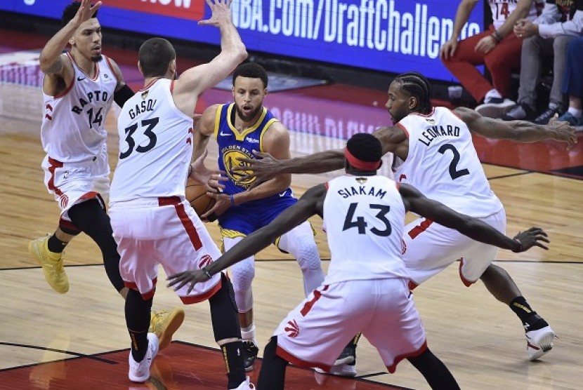 Pemain Warriors Stephen Curry mencoba melewati pemain Raptors.