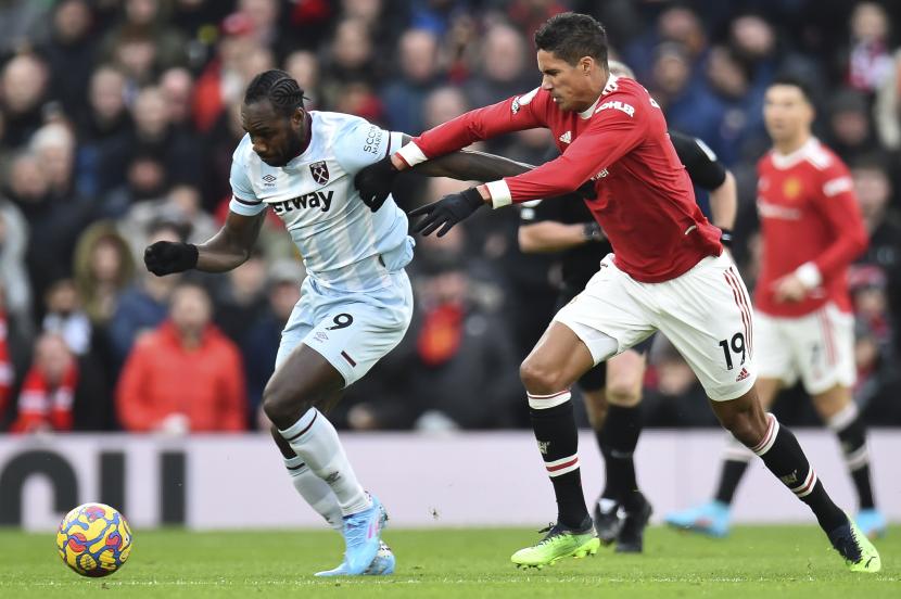 Pemain West Ham United Michail Antonio (kiri) berduel dengan bek MU Raphael Varane pada laga di Liga Primer Inggris, Old Trafford, Sabtu (22/1/2022).