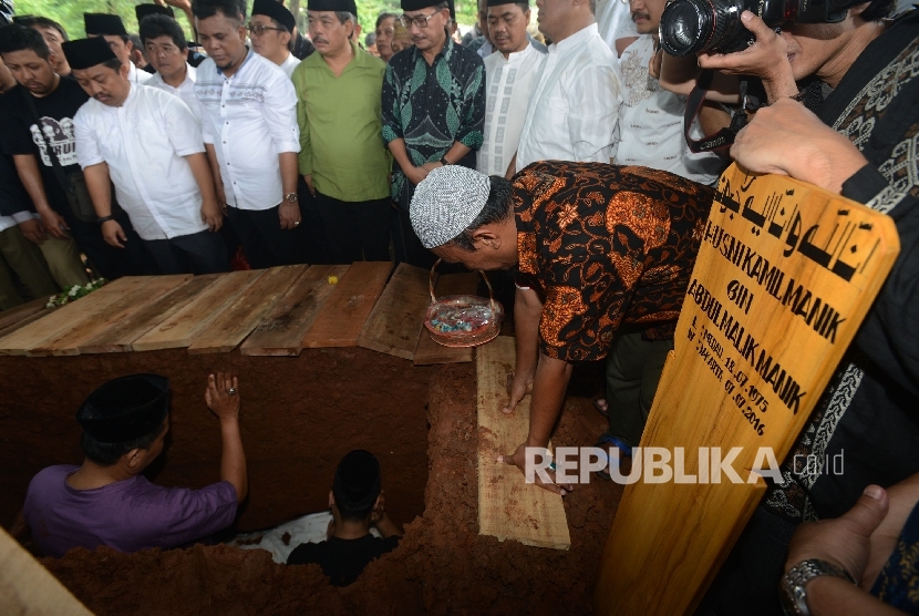 Pemakaman Ketua KPU Husni Kamil Manik bersama anaknya menyaksikan almarhum dikebumikan di TPU Jeruk Purut, Jakarta Selatan, Jumat (8/7).(Republika/Raisan Al Farisi)