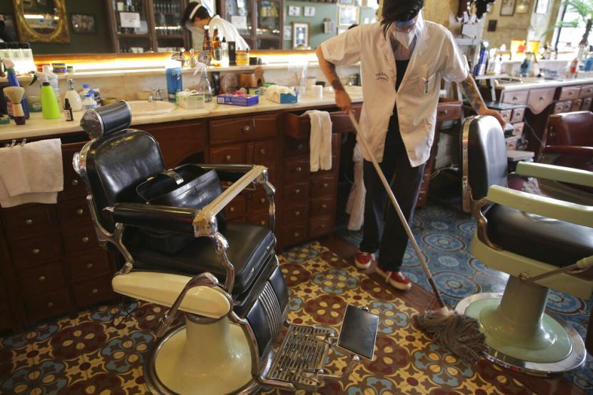 Pemangkas rambut tengah membersihkan rumah pangkasnya di Lisbon, Portugal, Senin (4/5). Pekerja migran di Portugal terpukul selama pandemi Covid-19.