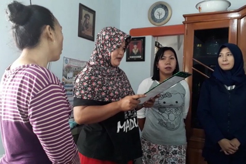 Ketua Kelompok Walet Ida Husniah membantu menghitung angsuran di hadapan anggota kelompok di pertemuan mingguan kelompok nasabah Mekaar PNM di Kelurahan Pakis, Banyuwangi, Jawa Timur.