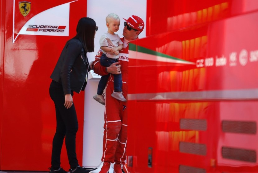 Pembalap Ferrari, Kimi Raikkonen bersama istri, Minttu Virtanen sambil menggendong anaknya, Robin pada sesi tes pramusim di sirkuit Catalunya, Barcelona, Spanyol, Jumat (10/3). Raikkonen menjadi yang tercepat pada tes pramusim tahun ini.