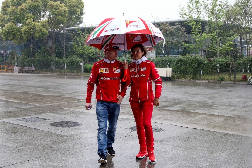 Pembalap Ferrari, Kimi Raikkonen (kiri) berjalan di paddock sirkuit Shanghai, Cina, Kamis (6/4). Cuaca buruk mengakibatkan dibatalkannya sesi latihan bebas GP Cina pada hari ini.