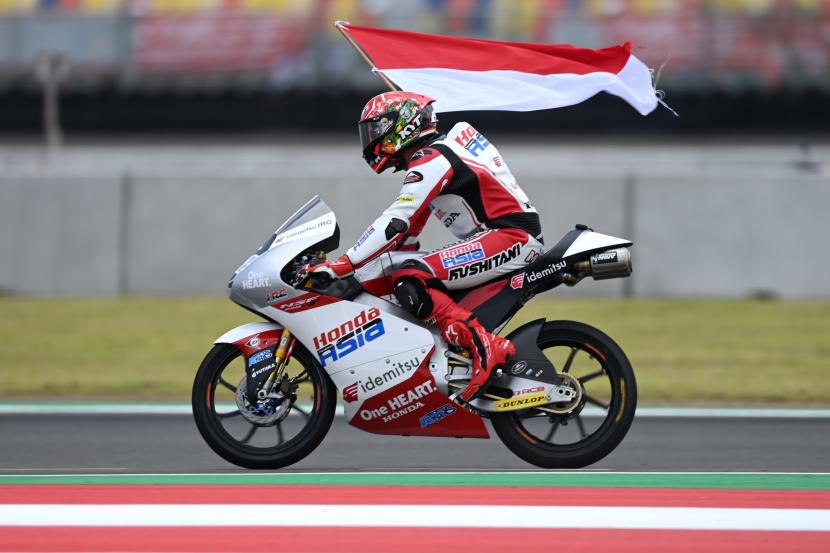 Pembalap Honda Team Asia asal Indonesia, Mario Suryo Aji, membawa bendera merah putih seusai balapan Moto3.