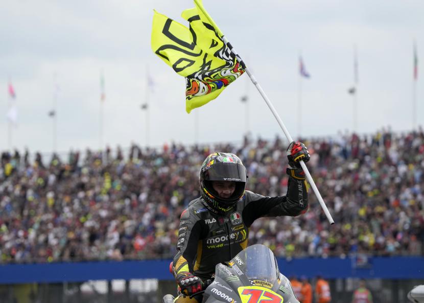 Pembalap Italia Marco Bezzecchi dari Mooney VR46 Racing Team saat merayakan kemenangan di MotoGP dengan memegang bendera bernomor Valentino Rossi.