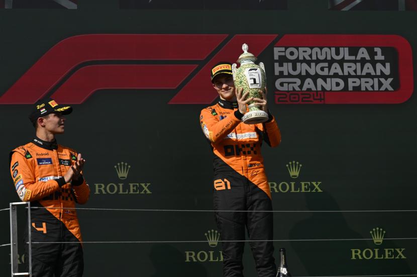 Pembalap McLaren Oscar Piastri asal Australia (kanan) merayakan kemenangannya di podium setelah memenangi balapan Grand Prix Formula Satu Hungaria di Sirkuit Hungaroring di Mogyorod, Hungaria, Ahad, 21 Juli 2024.