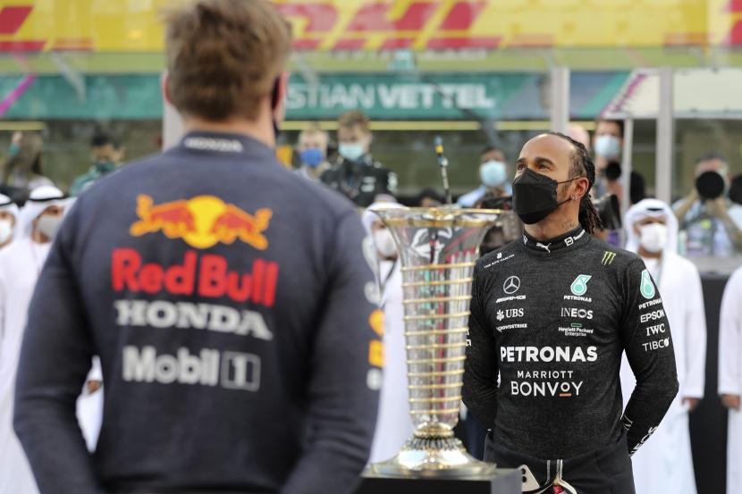 Pembalap Mercedes Lewis Hamilton dari Inggris, kanan, dan pebalap Red Bull Max Verstappen dari Belanda berbaris di grid sebelum Grand Prix Formula Satu Abu Dhabi di Abu Dhabi, Uni Emirat Arab, Ahad 12 Desember 2021.