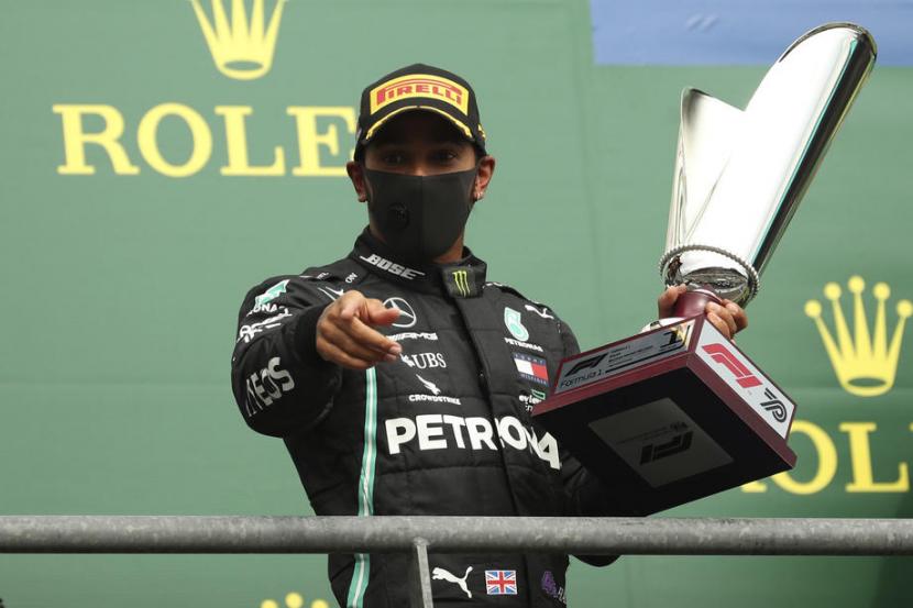 Pembalap Mercedes, Lewis Hamilton memegang trofi juara GP Belgia, Ahad (30/8).