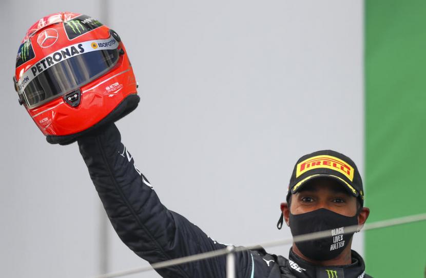 Pembalap Mercedes, Lewis Hamilton mengangkat helm berwarna merah milik Michael Schumacher sebagai hadiah atas pencapaian rekornya yang melampaui 91 kemenangan Schumacher. Pada balapan F1 di Sirkuit Nurburging, Jerman, Ahad (11/10), Hamilton finis terdepan.
