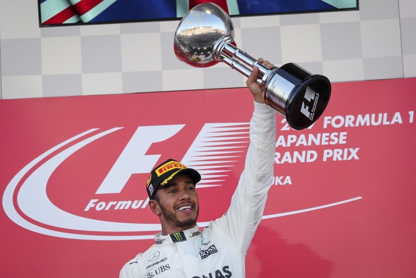 Pembalap Mercedes, Lewis Hamilton mengangkat trofi juara GP Jepang setelah menjadi yang tercepat pada balapan di Sirkuit Suzuka, Ahad (8/10).