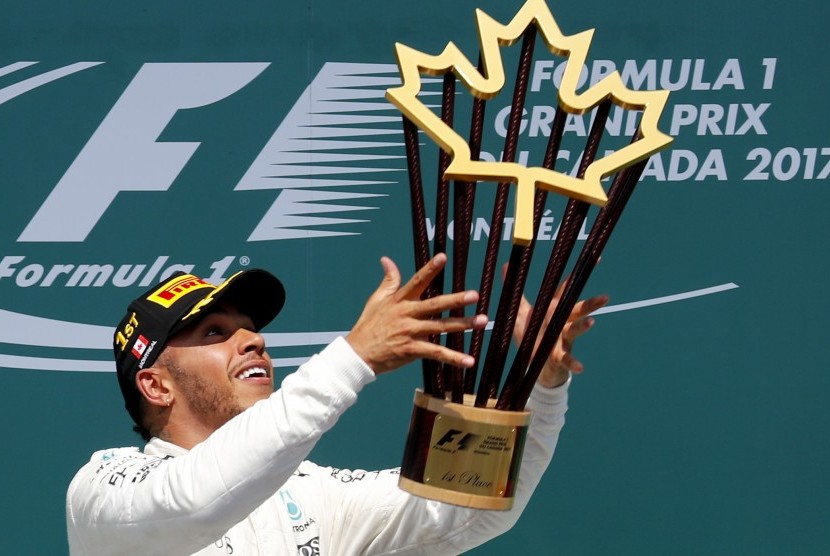 Pembalap Mercedes, Lewis Hamilton mengangkat trofi juara GP Kanada di Sirkuit Gilles Villeneuve, Ahad (11/6).