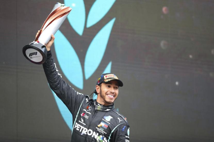 Pembalap Mercedes, Lewis Hamilton mengangkat trofi juara GP Turki setelah berhasil finis terdepa, Ahad (15/11). Atas kemenangan di GP Turki, Hamilton meraih gelar juara duni F1 musim 2020.