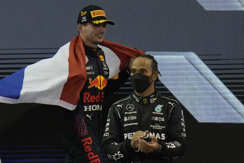 Pembalap Red Bull Max Verstappen dari Belanda melakukan selebrasi setelah menjadi juara dunia setelah memenangkan Formula Satu Grand Prix Abu Dhabi di Abu Dhabi, Uni Emirat Arab, Ahad (12/12). Di sebelah kanan adalah posisi kedua pembalap Mercedes Lewis Hamilton dari Britania.
