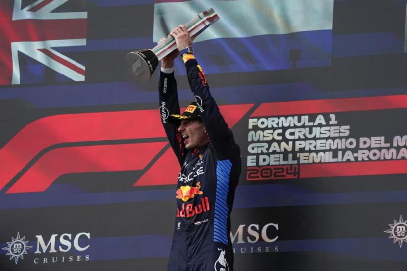 Pembalap Red Bull Racing Max Verstappen mengangkat trofi juara GP Emilia Romagna, di Sirkuit Imola, Italia, Ahad (19/5/2024). Verstappen mencatatkan waktu tercepat satu jam 25 menit 25,252 detik, unggul tipis 0,725 detik atas Lando Norris.