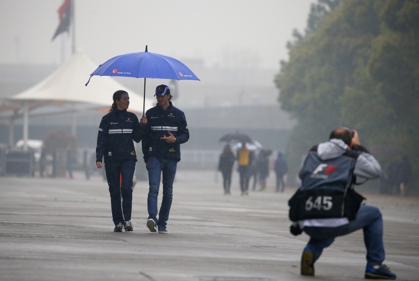 Pembalap Sauber, Antonio Giovinazzi (kedua kiri) berjalan di sirkuit Shanghai yang diguyur hujan, Kamis (6/4). Sesi latihan bebas GP Cina pada hari ini dibatalkan akibat cuaca buruk.