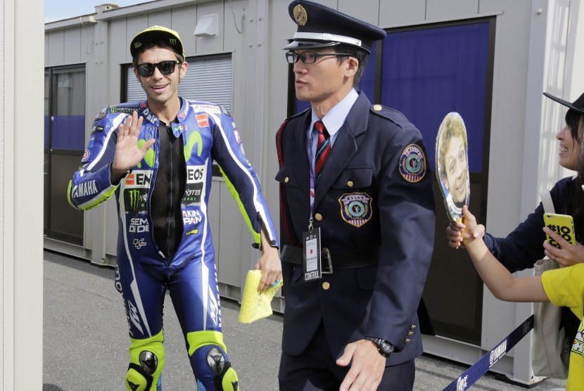 Pembalap Yamaha Movistar, Valentino Rossi (kiri) melambaikan tangan kepada fan saat sesi latihan bebas MotoGP di sirkuit Motegi, Jepang, Jumat (14/10). Rossi berada di urutan ketujuh.