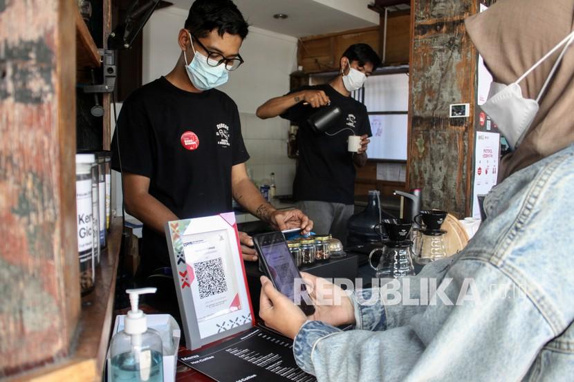 Pembeli membayar dengan metode scan Quick Response Code Indonesian Standard (QRIS) di Kafe kawasan Sidoarjo, Jawa Timur, Jumat (13/8/2021). Masyarakat Indonesia telah familiar dengan teknologi pembayaran nirsentuh seperti e-money. 