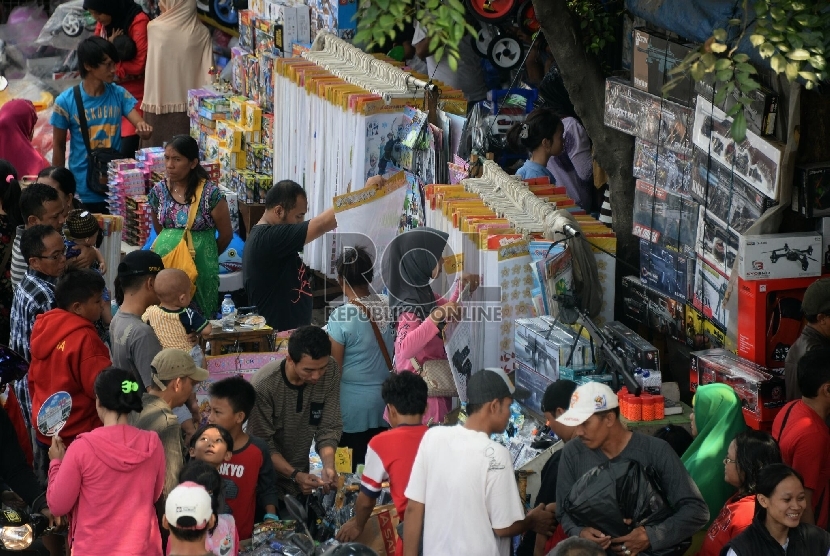 Pembeli memilih mainan untuk anaknya ketika berbelanja di Pasar Gembrong, Jakarta, Ahad (19/7).  (Republika/Prayogi)