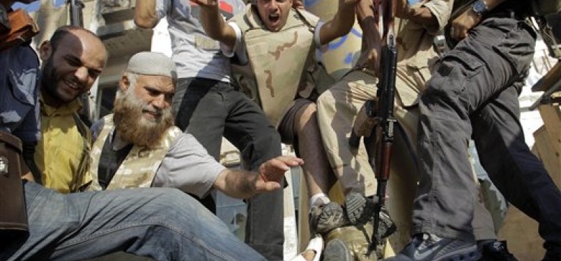 Pemberontak Libya menginjak-injak kepala patung Moammar Qaddafi.