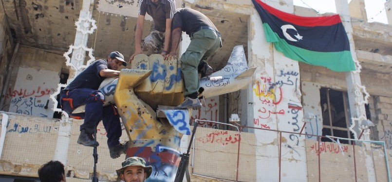 Pemberontak memanjat monumen di kamp kediaman Moammar Qaddafi, Bab Al-Aziziya, di Tripoli, Kamis (25/8). Keberadaan Qaddafi dan keluarganya belum diketahui.