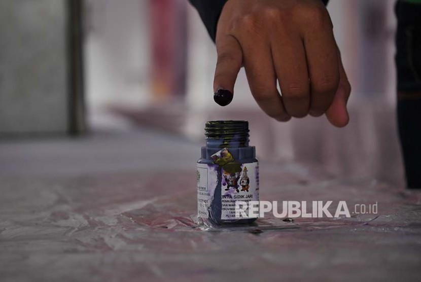 Pemilih mencelupkan jari ke botol tinta pemilu di sebuah TPS di Jatipadang pada Pilkada DKI Putaran 2, Rabu (19/2).