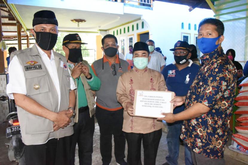 Pemilik UD Farhan, Yendrawadi (kanan) menyerahkan zakat yang diterima oleh Pembina LAZ Ar Risalah Charity, Ustadz Mulyadi Muslim (kedua dari kanan), disaksikan oleh Walikota Padang, Mahyeldi Ansharullah (kiri).