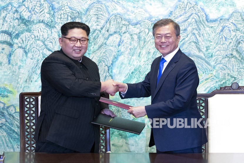 Pemimpin Korea Utara Kim Jong Un, kiri, dan Presiden Korea Selatan Moon Jae-in berjabat tangan setelah menandatangani pernyataan bersama di desa perbatasan Panmunjom di Zona Demiliterisasi, Korea Selatan, Jumat (27/4).