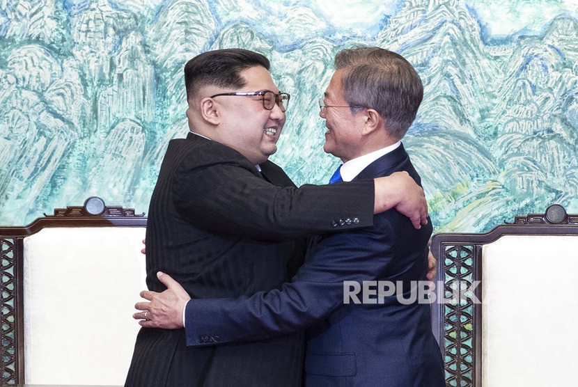 Pemimpin Korea Utara Kim Jong Un, kiri, dan Presiden Korea Selatan Moon Jae-in saling berpelukan setelah menandatangani pernyataan bersama di desa perbatasan Panmunjom di Zona Demiliterisasi, Korea Selatan, Jumat (27/4).