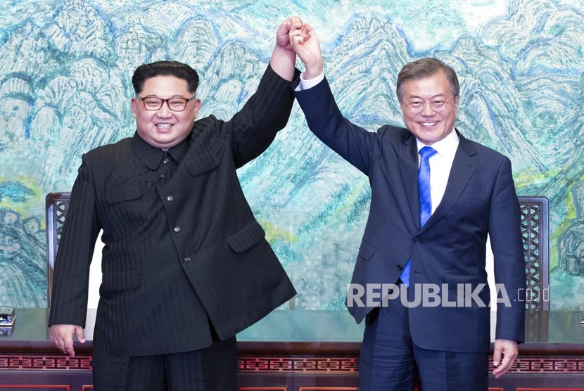 Pemimpin Korea Utara Kim Jong Un, kiri, dan Presiden Korea Selatan Moon Jae-in mengangkat tangan mereka setelah menandatangani pernyataan bersama di desa perbatasan Panmunjom di Zona Demiliterisasi, Korea Selatan, Jumat (27/4).