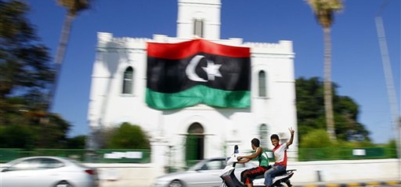 Pemuda Libya mengacungkan jari tangan tanda kemenangan ketika melintas di depan gedung Al-Ajaylat yang kini dikuasai pemberontak, sekitar 120 kilometer barat Tripoli, Libya.