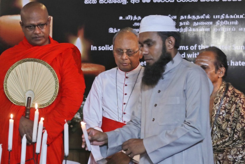 Pemuka agama Islam Sri Lanka menyalakan lilin dalam acara solidaritas kepada korban pengeboman saat Paskah di Kolombo, Sri Lanka, Ahad (28/4). Di belakangnya tampak biksu Budha, biksu Hindu, dan pendeta Kristen.