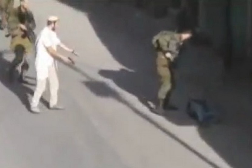 Pemukim Israel memegang pistol setelah menembak pria Palestina, Sabtu (17/10)