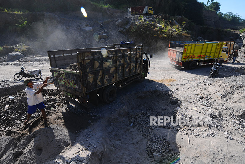 Penambang menaikkan pasir ke dalam bak truk di lereng Gunung Merapi. 