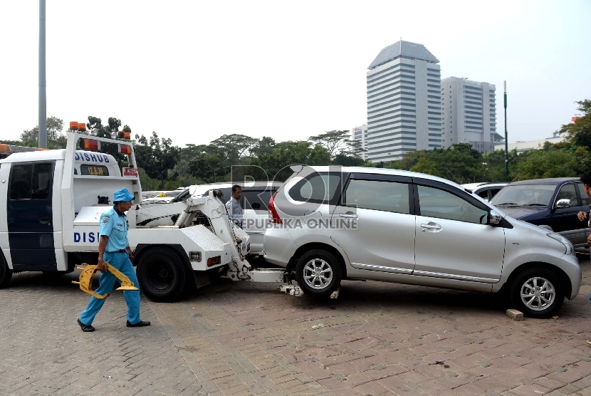 Penampuangan Derek Parkir Liar. Petugas menggembok ban mobi hasil razia parkir di Parkir IRTI Monas, Jakarta Pusat, Rabu (1/7). (Republika/Wihdan)