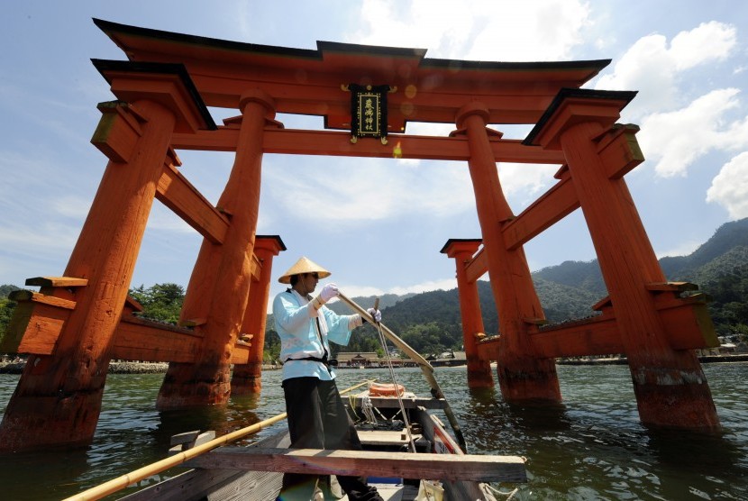 Pendayung perahu melintasi gerbang kayu O-Torii dari kuil Itsukushima di Pulau Miyajima, 20 km dari Hiroshima. Kuil Shinto ini sudah ada sejak abad ke-6 dan bangunan yang kini ada berdiri sejak abad ke-12.