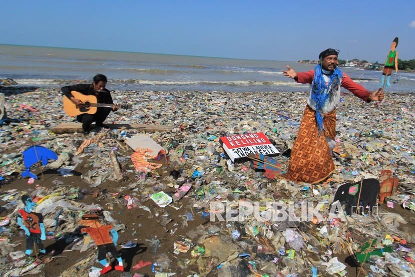 Pendongeng sekaligus seniman tutur Samsudin (kanan) melakukan aksi teatrikal dengan latar belakang tumpukan sampah plastik di Pantai Dadap, Juntinyuat, Indramayu, Jawa Barat, Sabtu (6/5/2021). Aksi teatrikal dalam rangka memperingati Hari Lingkungan Hidup Sedunia itu untuk mengkritisi pengelolaan sampah plastik di Indonesia. 