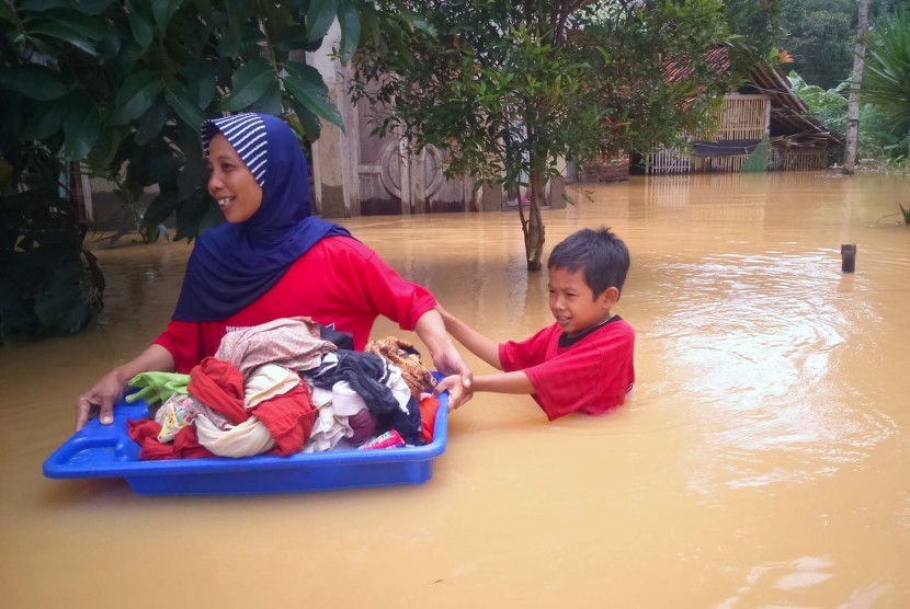 Penduduk berjalan digenangan banjir luapan Sungai Citanduy dan Cikidang, di Desa Tanjungsari, Kecamatan Sukaresik, Kabupaten Tasikmalaya. 