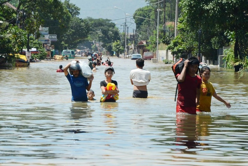 Penduduk berjalan digenangan banjir luapan Sungai Citarum yang menggenangi Jalan Moh Toha, Kabupaten Bandung, Selasa (15/3). (Republika/Edi Yusuf)