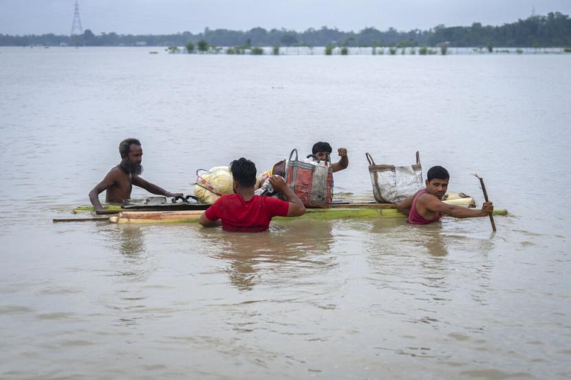 Penduduk desa membawa barang-barang mereka di atas rakit pisang dan mengarungi banjir di desa Korora, barat Gauhati, India, Jumat, 17 Juni 2022.