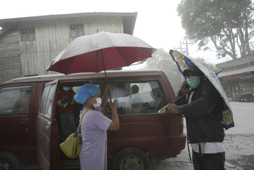  Penduduk desa menggunakan masker dan payung untuk melindungi diri dari abu vulkanik letusan Gunung Sinabung saat mereka meninggalkan rumah mereka di Karo, Sumatera Utara, Selasa (17/9).     (AP/Binsar Bakkara)