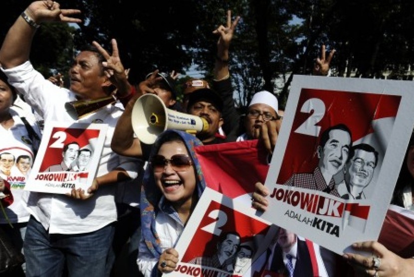 Pendukung Capres Joko Widodo dan Cawapres Jusuf Kalla memegang poster dengan urut dua usai penentuan nomor urut pasangan capres dan cawapres pada pilpres pada 9 Juli mendatang di depan Gedung KPU Jakarta, Ahad (1/6).