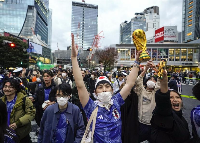  Pendukung Jepang merayakan dengan mockup trofi Piala Dunia setelah Jepang mengalahkan Spanyol selama pertandingan sepak bola grup E Piala Dunia FIFA 2022 Qatar untuk maju ke tahap berikutnya, di Shibuya Scramble Crossway di Tokyo, Jepang, Jumat, 2 Desember 2022. 