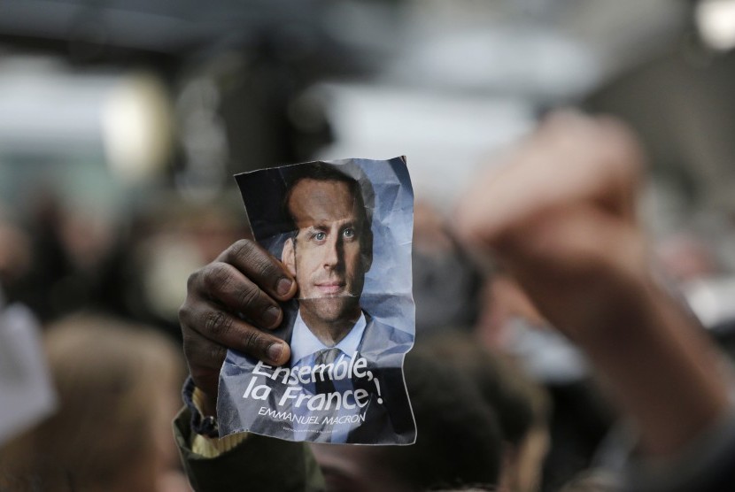  Pendukung kandidat calon presiden Emmanuel Macron mengangkat foto wajah Macron di Paris, Prancis. Jajak pendapat memproyeksikan Macron akan menjadi Presiden Prancis berikutnya, (7/5).