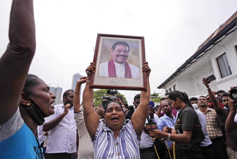 Pendukung pemerintah Sri Lanka meneriakkan slogan-slogan memegang potret Perdana Menteri Mahinda Rajapaksa di luar kediaman resminya di Kolombo, Sri Lanka, Senin, 9 Mei 2022. Pendukung pemerintah pada Senin menyerang pengunjuk rasa yang telah berkemah di luar kantor perdana menteri Sri Lanka, ketika serikat pekerja memulai 