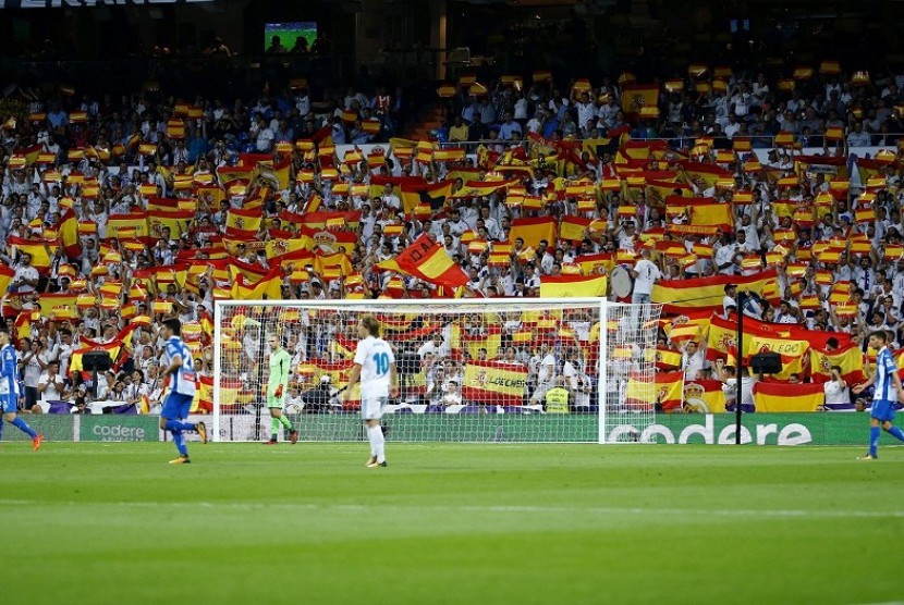 Pendukung Real Madrid mengibarkan bendera Spanyol saat melawan Espanyol, Senin (2/10) dini hari WIB.