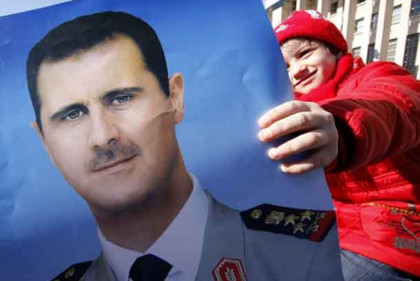 Pendukung rezim Suriah memegang poster Presiden Suriah Bashar Al-Assad.