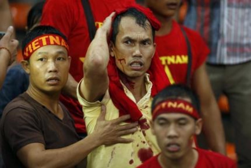 Pendukung Vietnam memegangi kepalanya yang terlukan terkena lemparan pendukung Malaysia dalam semifinal leg pertama Piala AFF 2014 di Kuala Lumpur, Ahad (7/12).