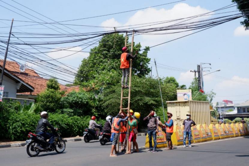 Pekerja menertibkan kabel optik di Jalan Tole Iskandar dan Jalan Siliwangi, Kota Depok, Rabu (30/9/2022).