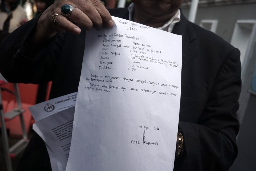 Pengacara terpidana mati Freddy Budiman, Untung Sunaryo, menunjukan surat permohonan grasi yang ditulis tangan di depan Dermaga Penyeberangan Wijayapura, Cilacap, Jateng, Rabu (27/7). 